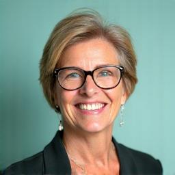 Portret dr Anny Kowalskiej, uśmiechniętej kobiety w średnim wieku z profesjonalnym i ciepłym wyrazem twarzy.